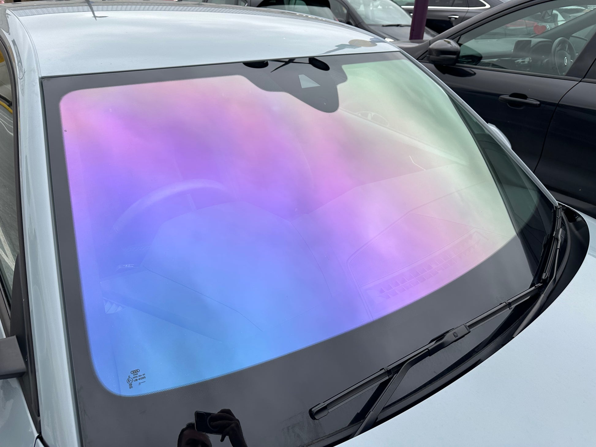 A car window with a purple, pink, and gold colored chameleon window film applied to it.