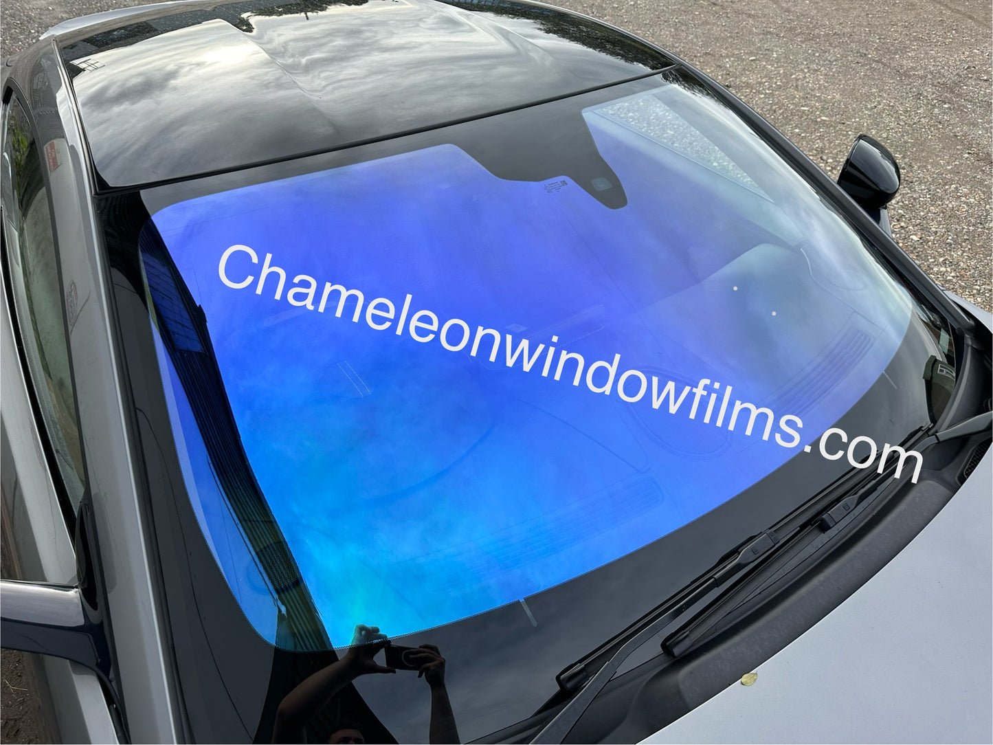 A car window with blue chameleon window film applied to it, showing a gradient of blue and purple colors.