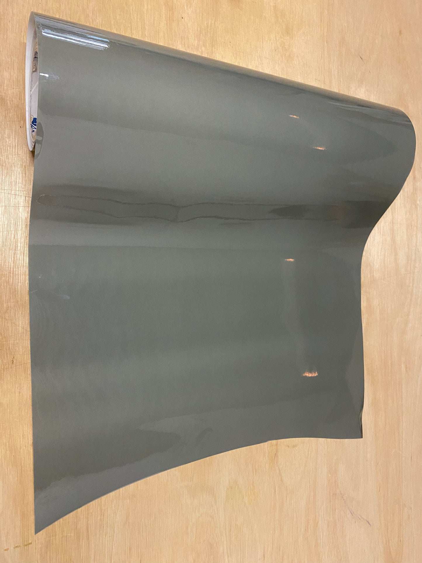 A roll of light tint film for vehicle tail lights placed on a wooden surface.