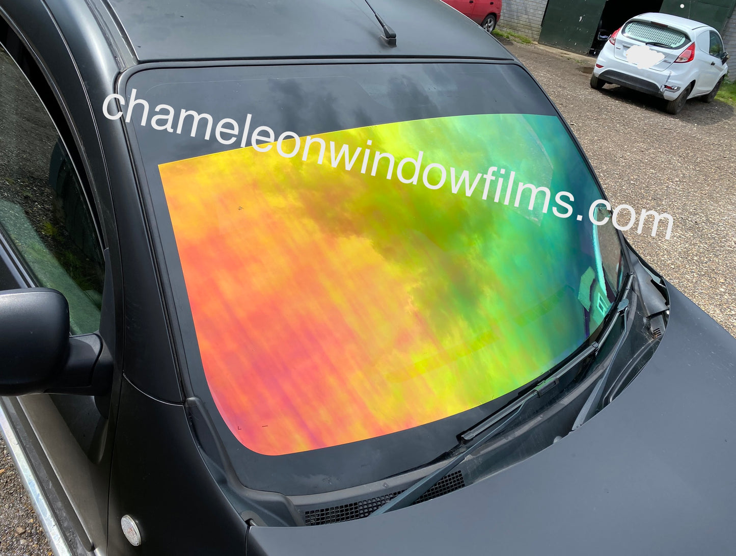 A multicolored chameleon window film with a yellow-red-green gradient applied to a vehicle's windshield.