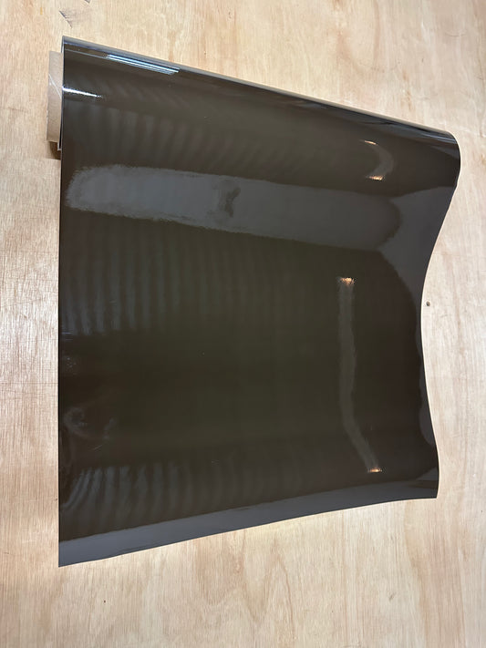 A piece of dark tint film for vehicle lights, displayed on a wooden surface.
