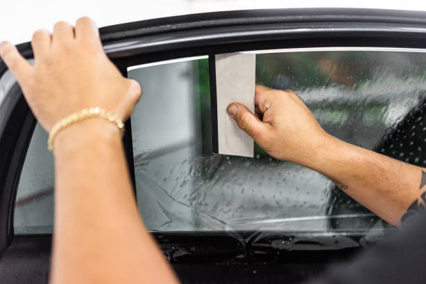 Person applying a car window film with a squeegee